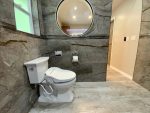 Infinity Eaze-Z3 bidet seat installed on a two-piece toilet in a modern bathroom, with the remote mounted on the wall