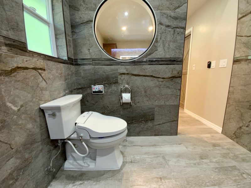 Infinity Eaze-Z3 bidet seat installed on a two-piece toilet in a modern bathroom, with the remote mounted on the wall