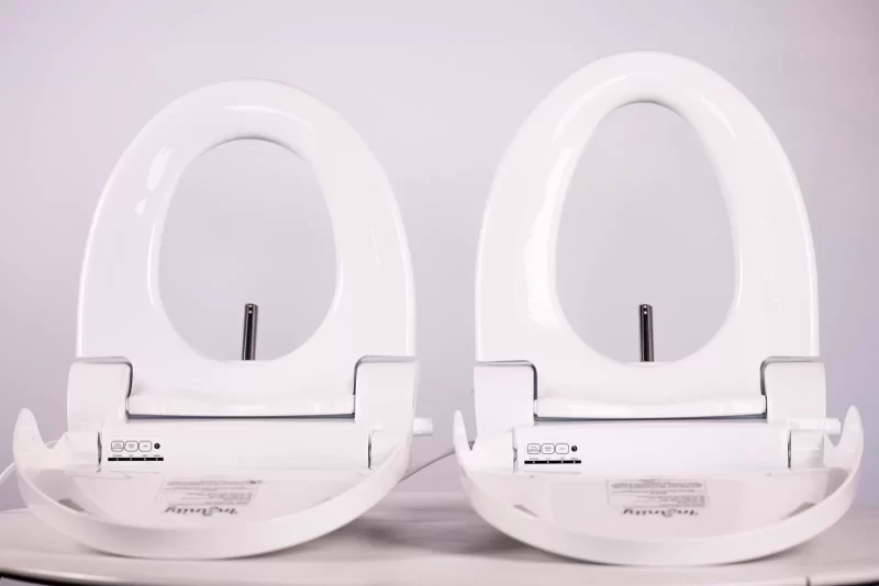 Round and elongated Infinity Eaze-Z3 bidet seats side by side with the seats lifted, showing the wash nozzles